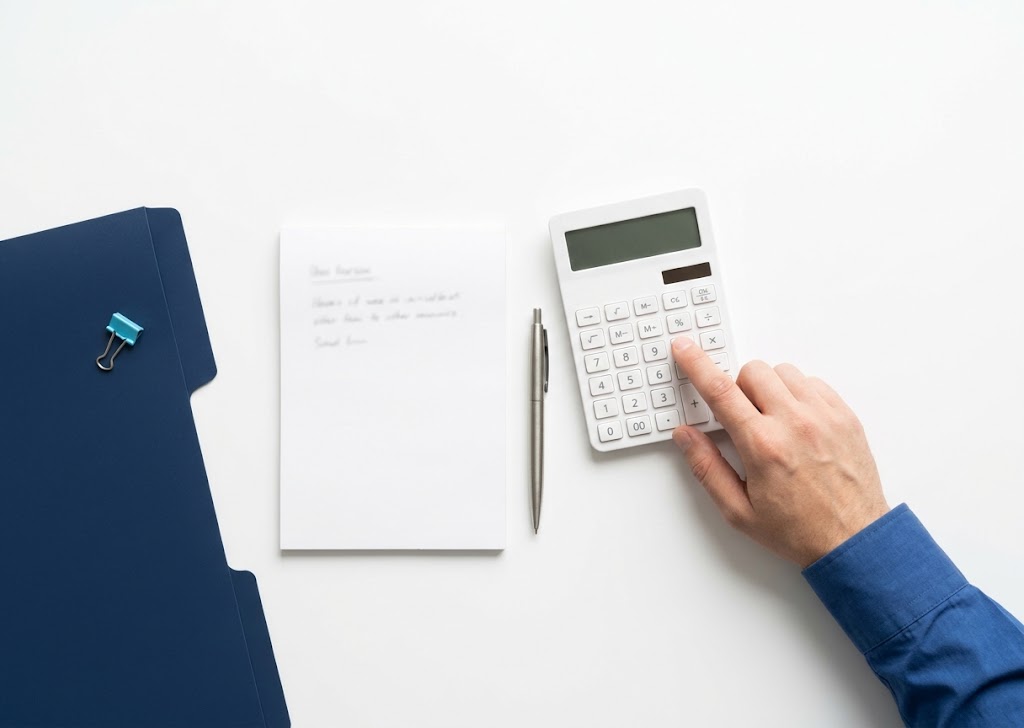 Calculator, notepad and pen on a desk for working out the cheapest week to convert a temp